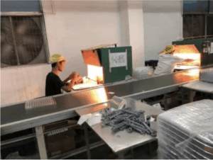 At a toy factory, workers with minimal protective equipment sit at machinery labeled "High temperature, be careful of burns."